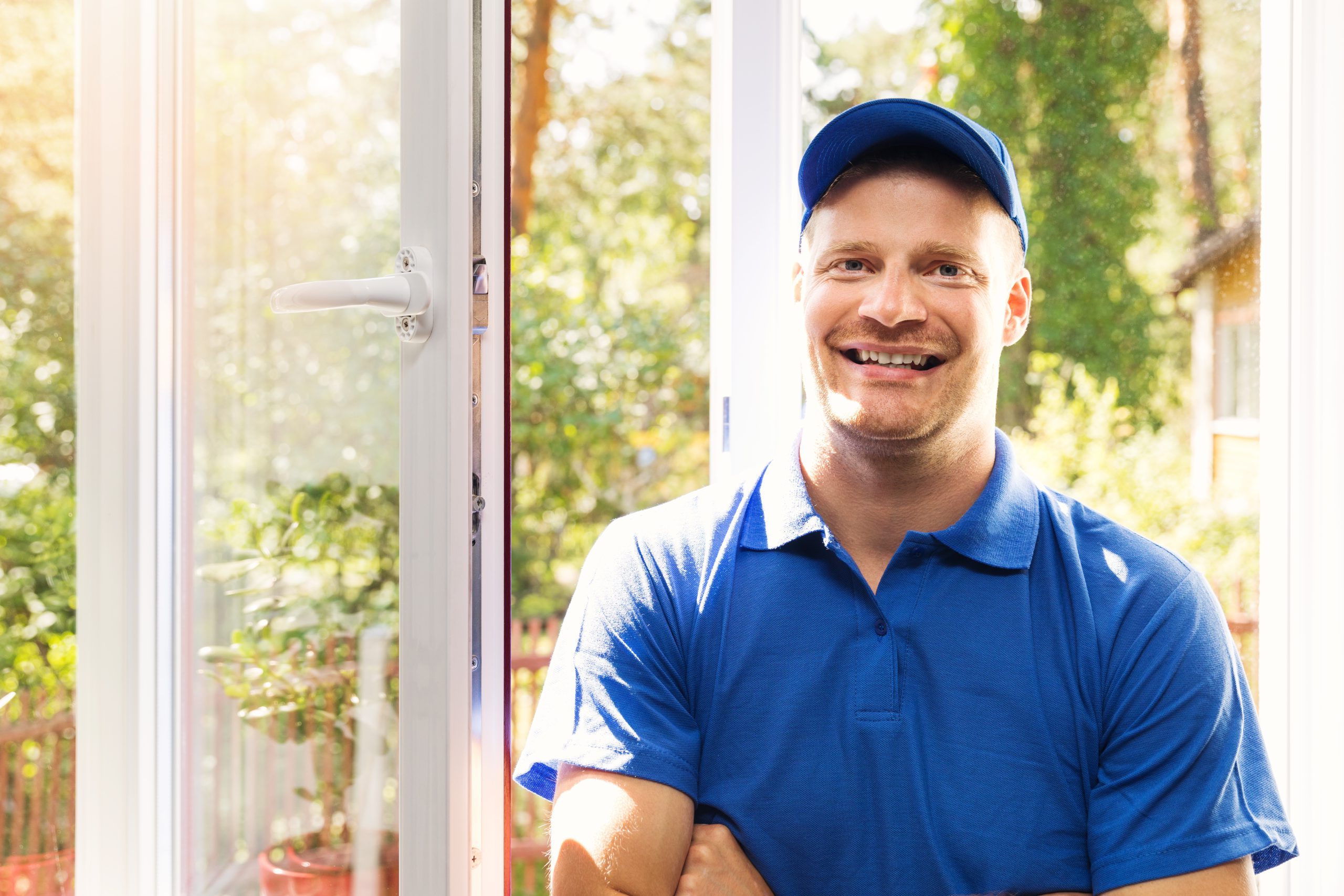  smiling window installer in blue uniform standing in the room